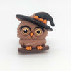 Brown 3D witch owl silicone focal bead wearing a black-and-orange witch hat while perched on a branch